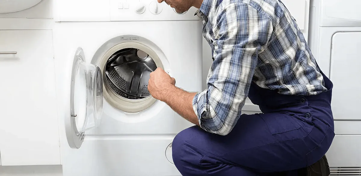 Handyman inspecting a dryer drum and internal parts for repair in Jackson, MS