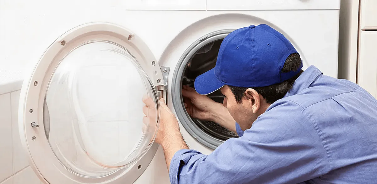 Washing machine repair handyman inspecting a front-load washer drum in Jackson, MS